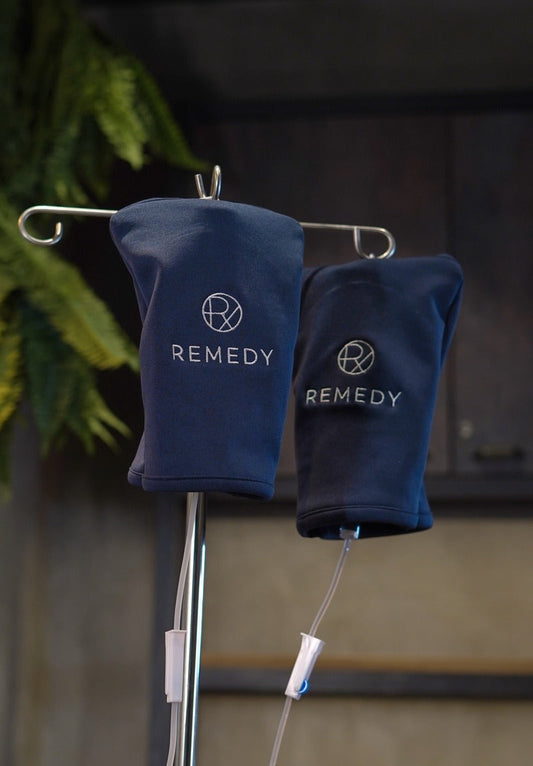 Two navy Remedy-branded IV drip bags hanging from a stainless steel stand